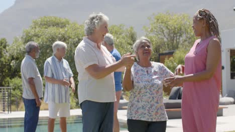 happy diverse senior female friends embracing at sunny garden party, unaltered, in slow motion