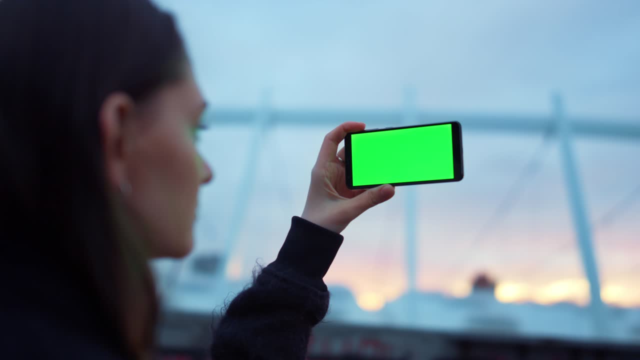 초록색 화면을 가진  ⁇ 드폰에서 사진을 찍는 소녀.  ⁇ 드폰을 사용하는 여인
