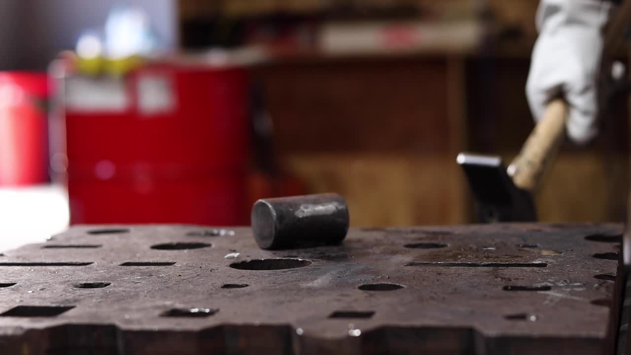 Blacksmiths forging hot metal with hammer in workshop