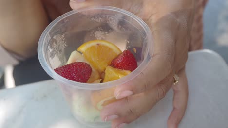 mujer comiendo una deliciosa ensalada de frutas al aire libre