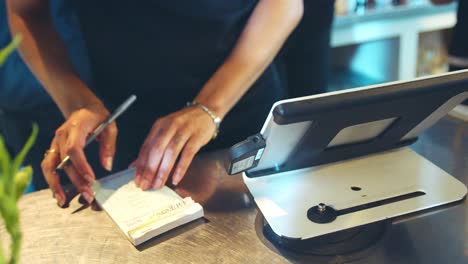 close up of waitress totaling bill at coffee shop checkout