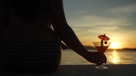 silhouette of a lady holds a glass of tropical drink beautiful sunset slow-mo 4k