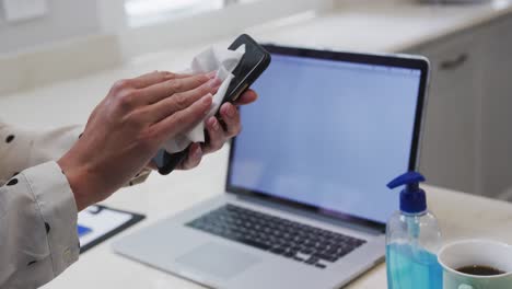 sección media de la mujer limpiando su teléfono inteligente con un pañuelo