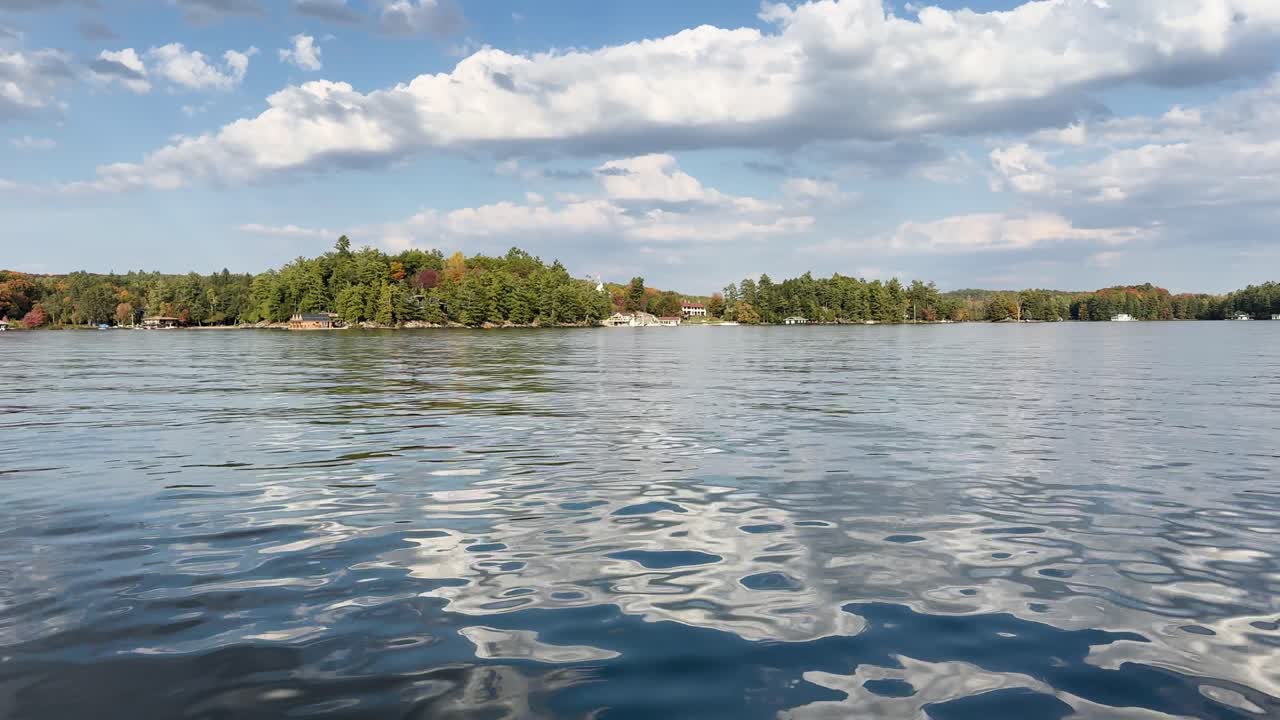 Wide shot of Muskoka lake shoreline with autumn forest captured from boat, Canada