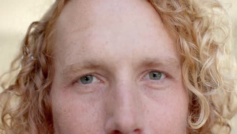 portrait close up of blue eyes of caucasian man with blonde curly hair smiling in slow motion