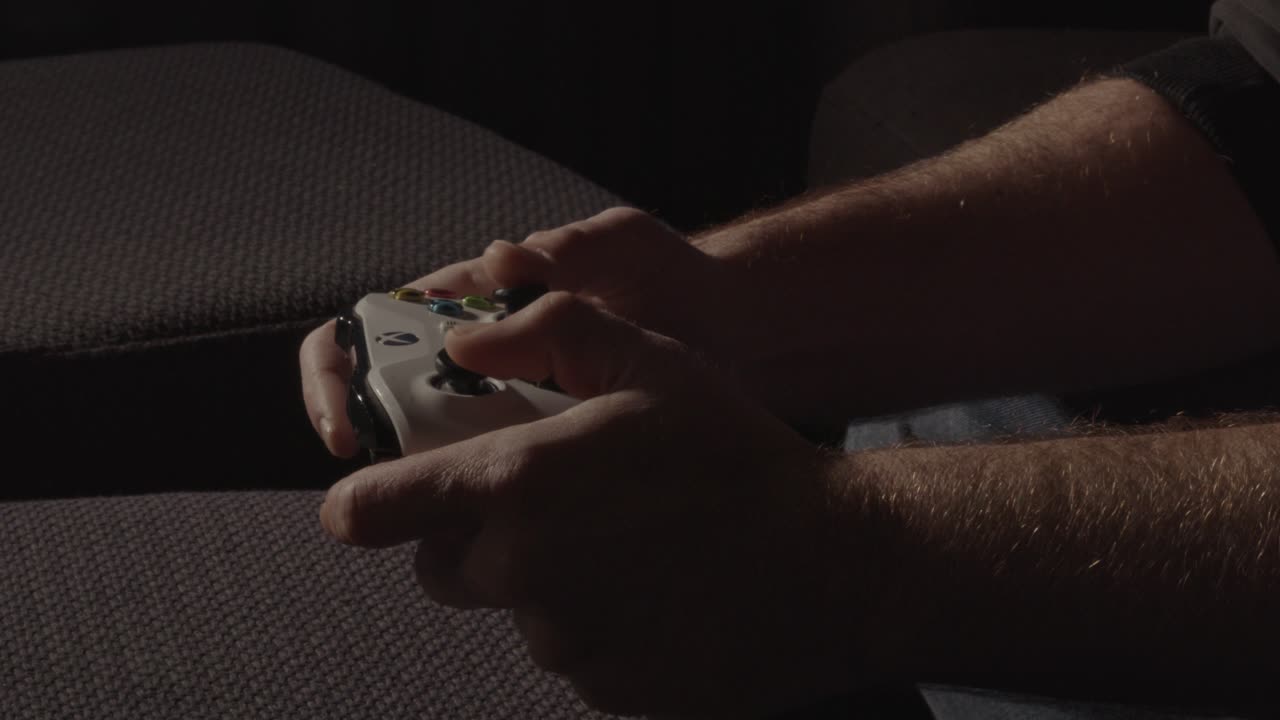 Hands playing with a videogame controller in a dark room