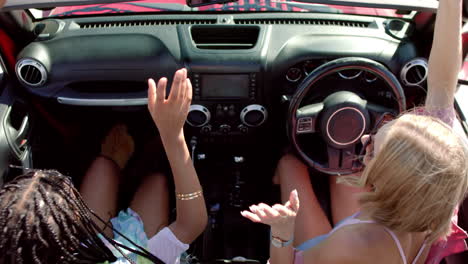 una joven afroamericana y una joven caucásica disfrutan de un día soleado en un coche en un viaje por carretera.
