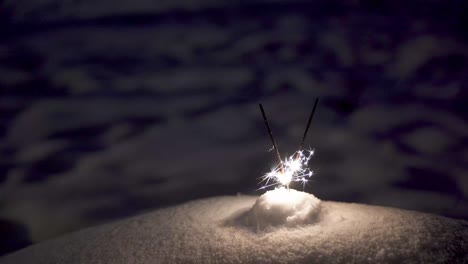 sparklers placed in the snow. bright sparkles of sparklers in the dark.