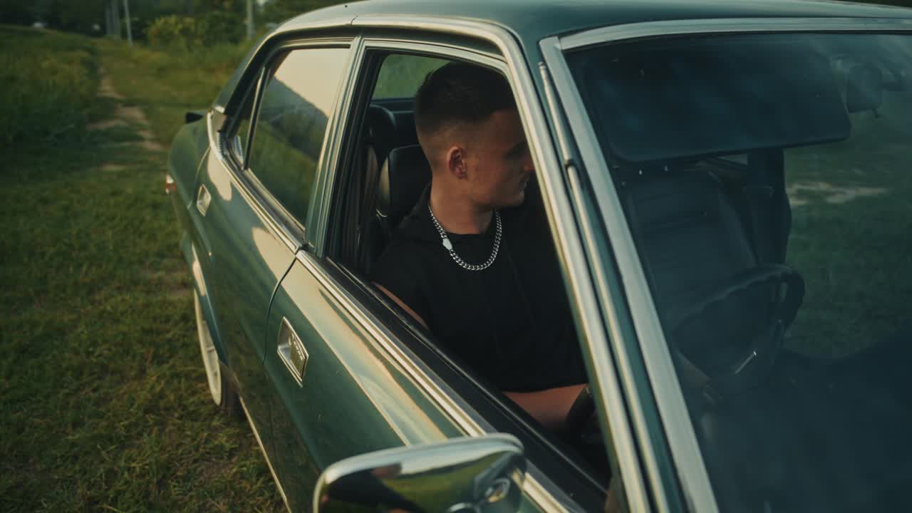 Man Driving a Vintage Green Car in a Field
