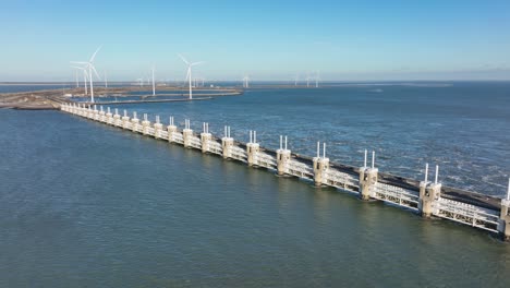 aerial slow motion shot of the eastern scheldt storm surge barrier and wind turbines in zeeland, the netherlands on a beautiful sunny day