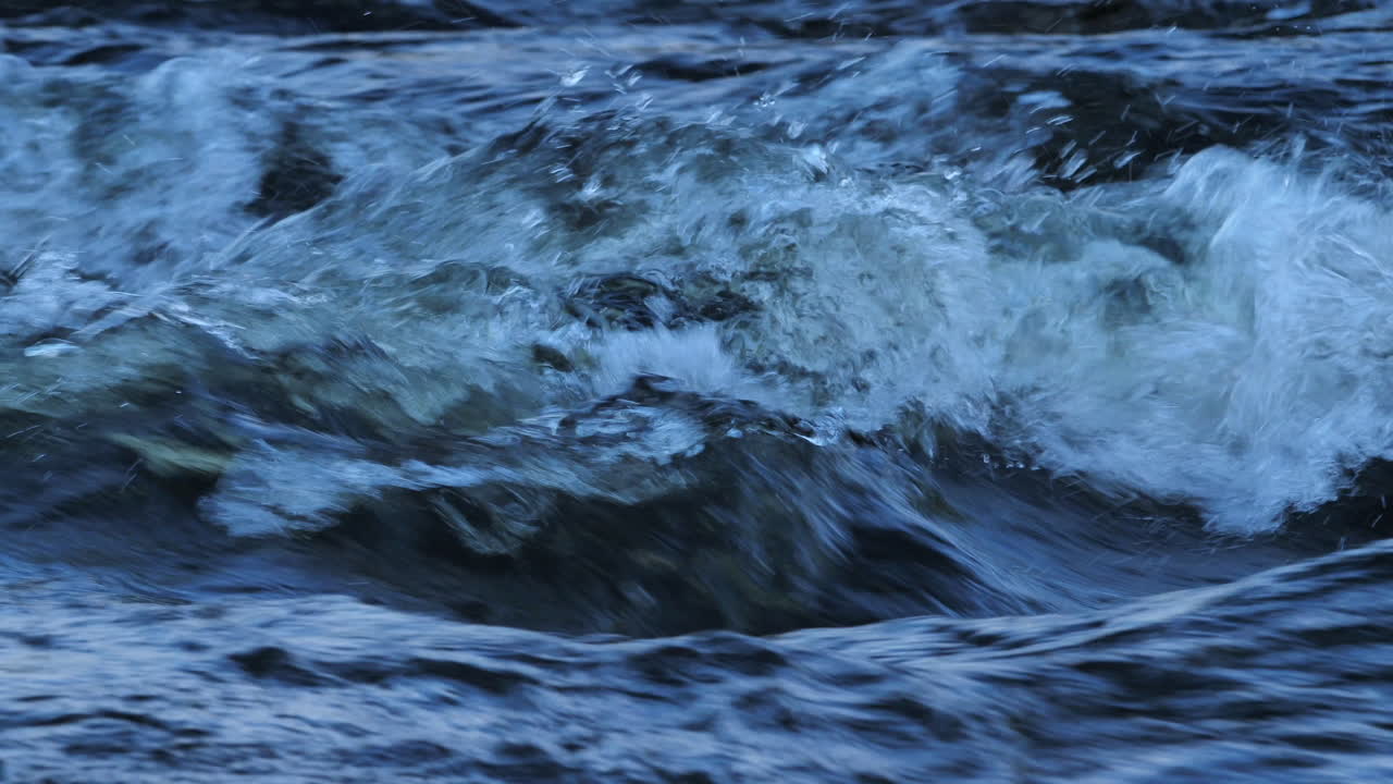 Close-up of freshwater rapids in Northumberland, UK. Slow motion bubbling detail and textured flow in a wild mountain stream