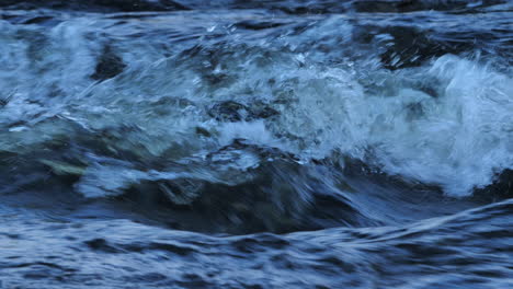 close-up of freshwater rapids in northumberland, uk. slow motion bubbling detail and textured flow in a wild mountain stream