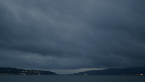 timelapse of heavy blue clouds passing and boats in the distance speeding past with their lights on