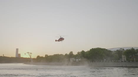operación de rescate en helicóptero rojo sobre el río al atardecer