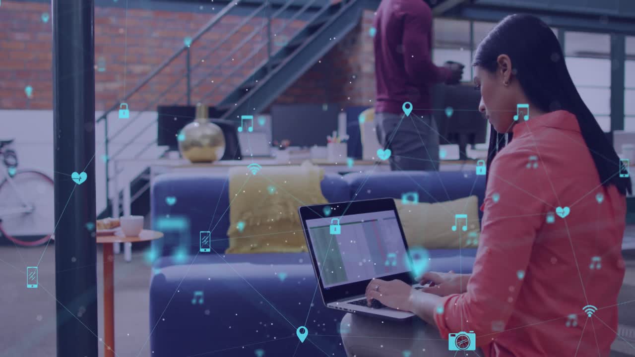 animação de uma rede de ícones digitais contra a visão traseira de uma mulher biracial usando um laptop no escritório
