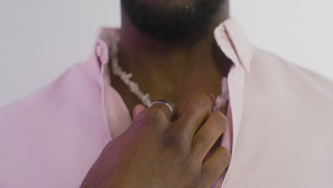 young handsome man looking at camera while plays with necklace