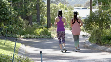 asian female friends running near forest on sunny day, slow motion