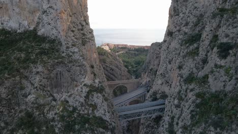 dolly aéreo entre rocas a puentes de mascarat en calpe, españa, mostrando el impresionante puente y el escarpado paisaje montañoso