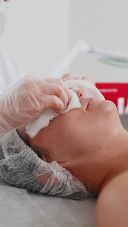 cosmetólogo médico limpia la cara y el cuello de la mujer procedimiento de limpieza con toallitas de algodón en la clínica de belleza