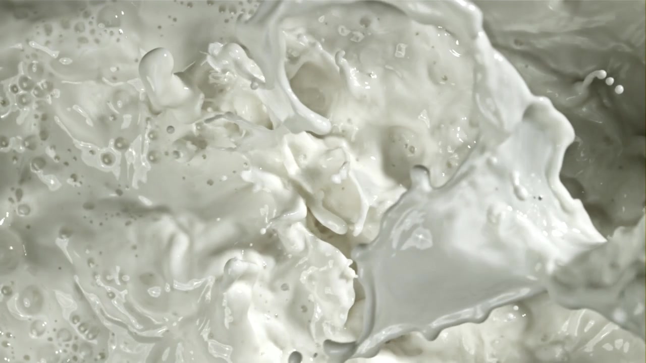 Primo piano di latte bianco che schizza e si increspa al rallentatore