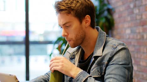 Man-using-digital-tablet-while-drinking-coffee