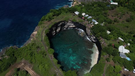 a hole of water surrounded by cliffs and greenery in nusa penida island, near bali