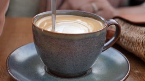 mujer disfrutando de un capuchino en un café