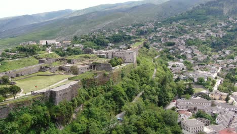 Drohnenansicht-In-Albanien,-Die-In-Der-Stadt-Gjirokaster-über-Eine-Mittelalterliche-Burg-Auf-Einer-Hochgelegenen-Festung-Fliegt-Und-Die-Ziegelbraunen-Dachhäuser-Zeigt