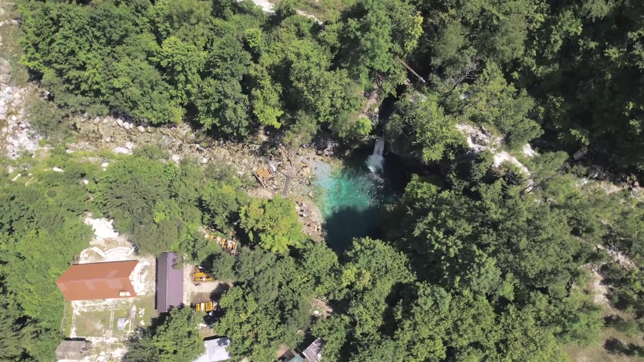 Ripresa aerea con drone in 4K del Blue Eye vicino a Theth, in Albania. L'acqua turchese cristallina circondata da una foresta verdeggiante e dalle spettacolari Alpi albanesi crea un paesaggio naturale mozzafiato
