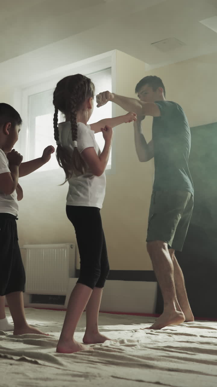 los niños hacen golpes siguiendo al entrenador en la escuela de boxeo. los pequeños deportistas golpeados por las manos bajo el control del instructor en el gimnasio en cámara lenta. desarrollo de los niños