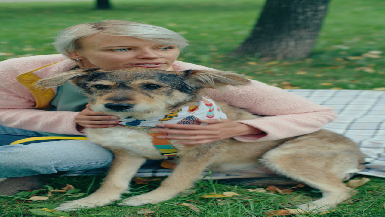 Woman Gently Embracing and Petting Dog on Grassy Lawn in Park