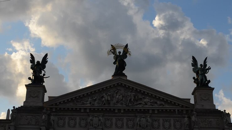 Teatro contro le nuvole. Leopoli, Ucraina. Esterno del Teatro dell'Opera e del Balletto di Leopoli. La scultura centrale è la Vittoria, quella a sinistra è la Musica, la figura a destra è la Commedia e il Dramma.