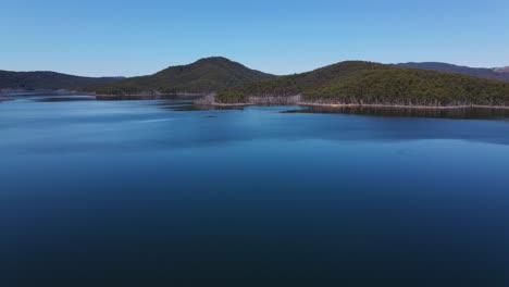 motionless blue water at advancetown lake surrounded by the mountains - hinze dam - advancetown, gold coast, qld, australia