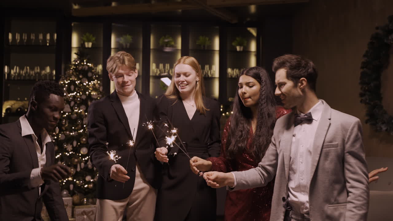 새해 전야 파티에서 춤추고 폭죽을 들고 있는 세련된 옷을 입은 친구들