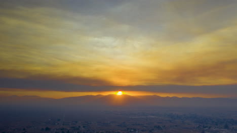 Hiperlapso-Aéreo-Nebuloso-De-La-Puesta-De-Sol-Sobre-El-Paisaje-Desértico-Cubierto-De-Humo-Del-Incendio-Del-Lago-En-El-Sur-De-California