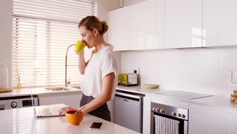 Frau-Benutzt-Laptop,-Während-Sie-In-Der-Küche-Kaffee-Trinkt