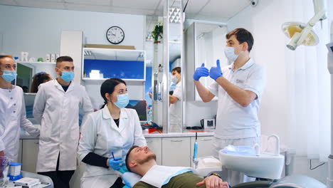 teacher of dentistry giving a practical lesson to students. one of the students sits near the patient.