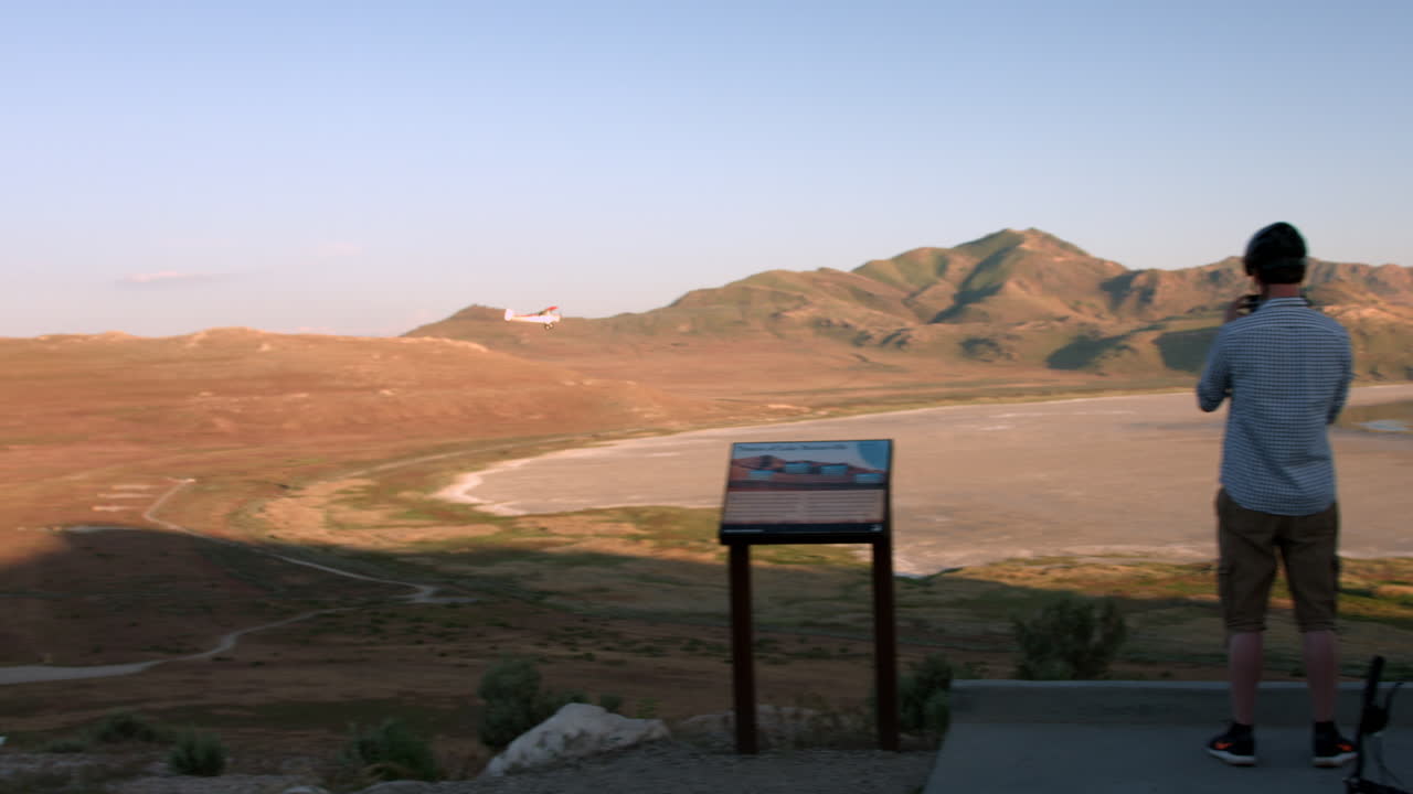 Three bikers point out a plane that is flying in front of them by a tourist spot