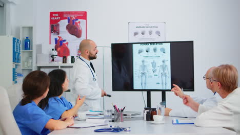 hombre experimentado médico analizando la imagen del esqueleto humano con colegas