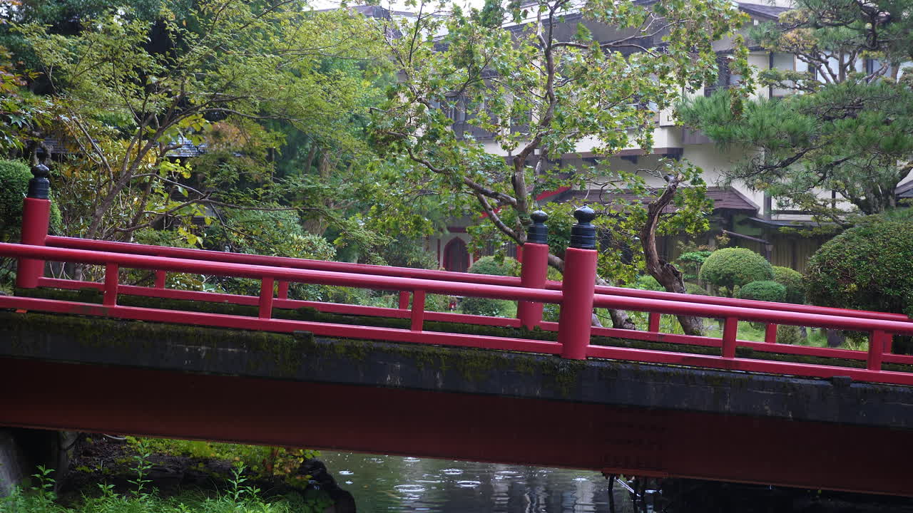 puente rojo sobre un estanque tranquilo en el jardín de koyasan, rodeado de exuberante vegetación, atmósfera serena