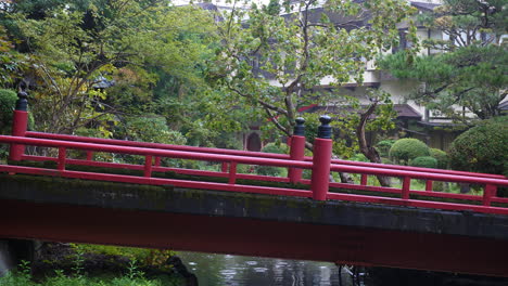 red bridge over tranquil pond in koyasan garden, surrounded by lush greenery, serene atmosphere