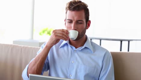 Businessman-working-on-laptop-and-drinking-espresso