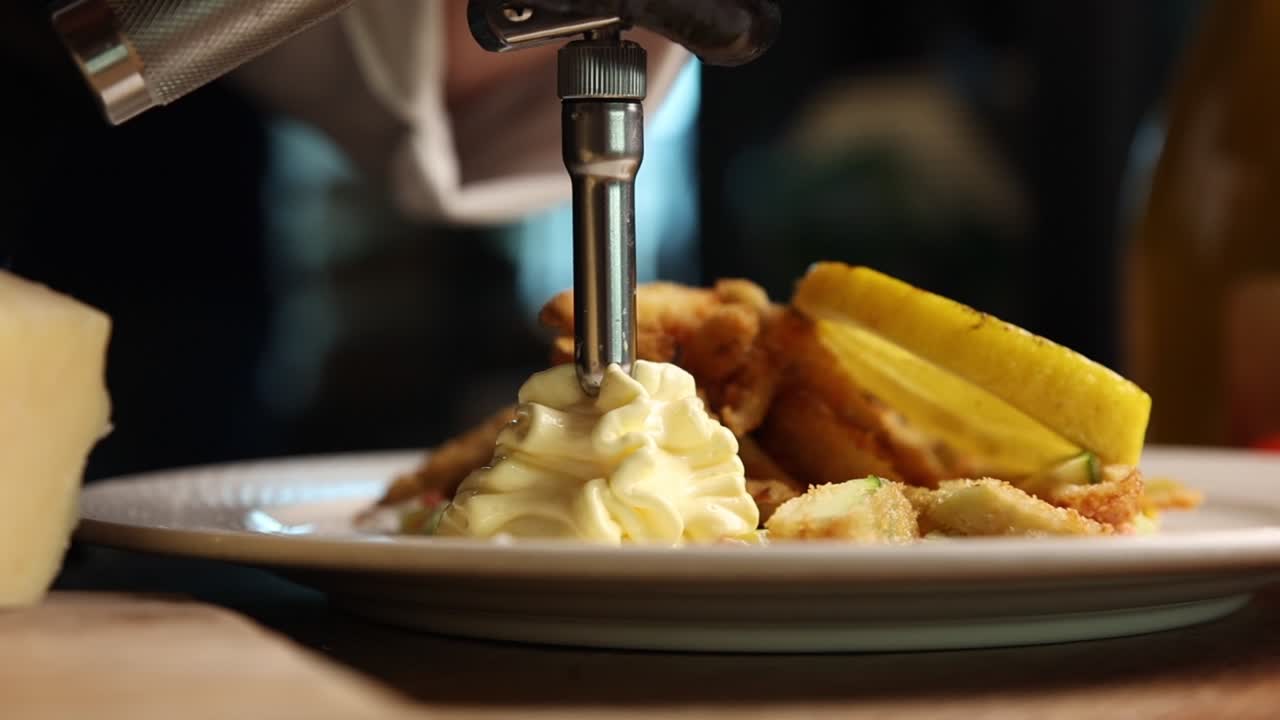 Chef Garnishing Fried Seafood Dish with Creamy Sauce