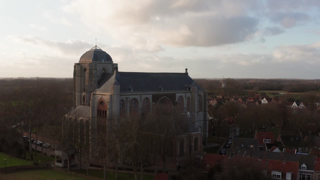 Revealing shot of the big Church of Veere from the canal. Low to high angle drone shot