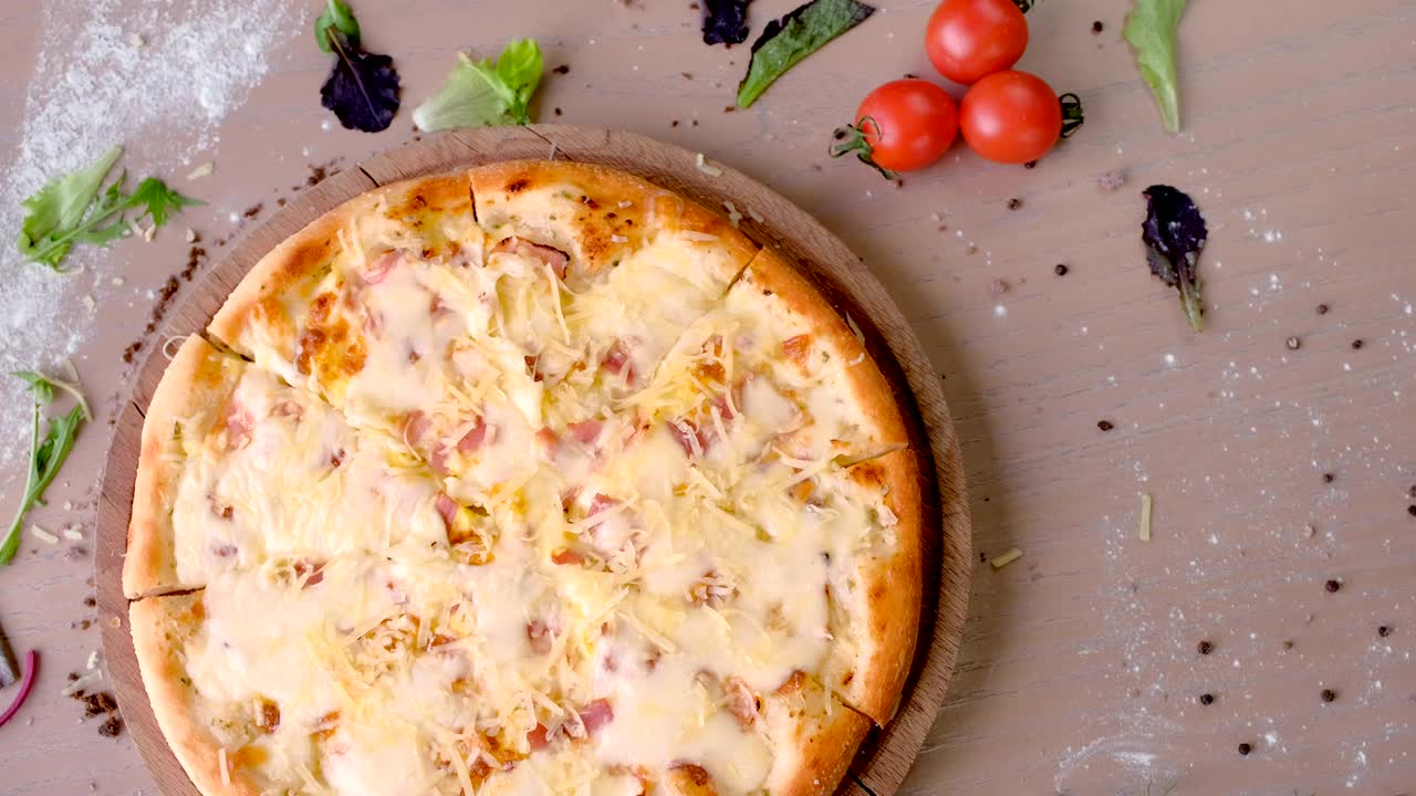 pizza con tocino y queso en una tabla de madera en la mesa.