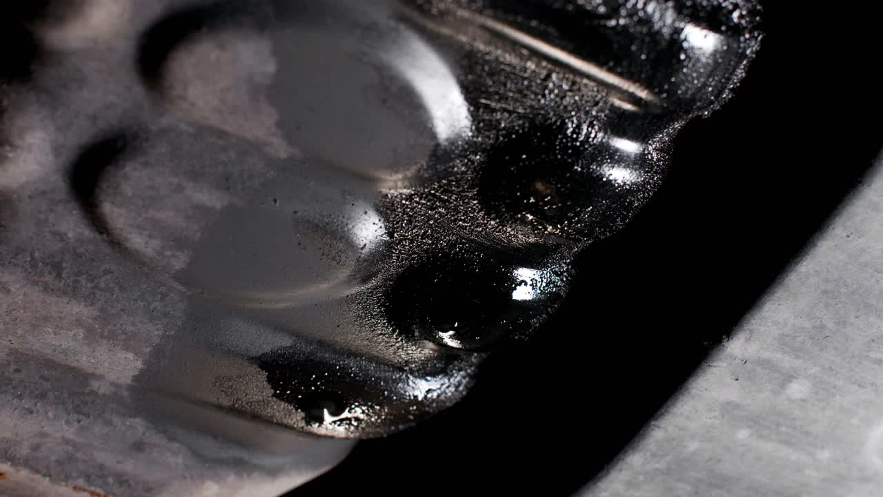 Detail close up of a leaking oil pan underneath a car. Rotating shot in 4K with movement.