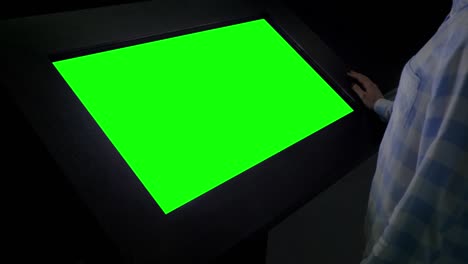 green screen concept - woman looking at blank green display kiosk at exhibition