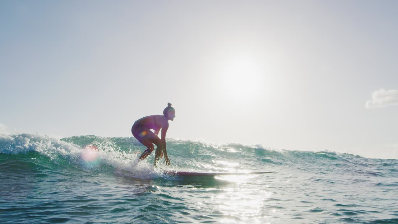 una mujer joven surfeando al atardecer.