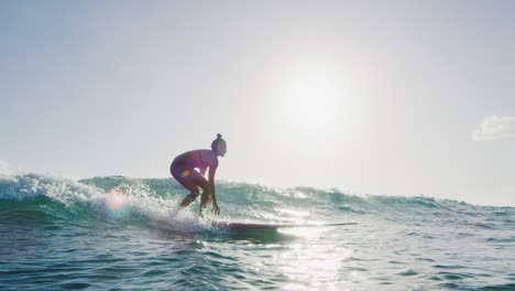 young woman surfing at sunset