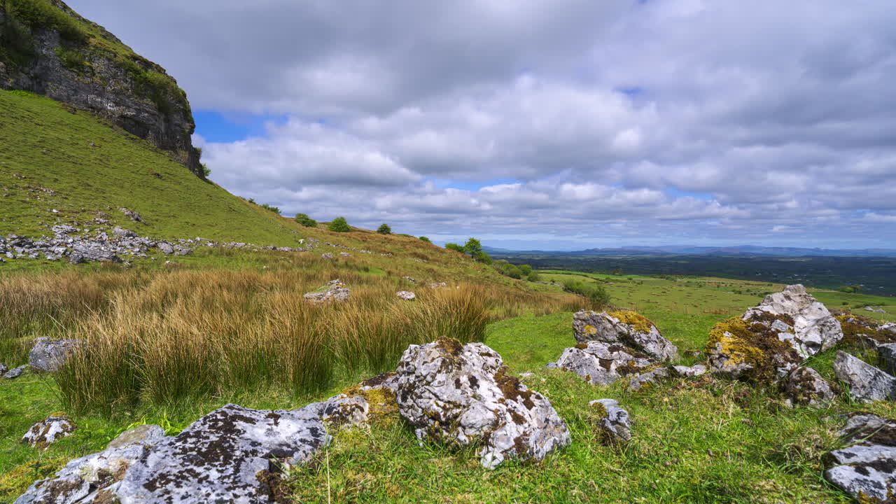 Timelapse af et landligt landskab med en klippeformation i forgrunden og bakker i det fjerne på en solrig og skyet dag, set fra Carrowkeel i County Sligo i Irland